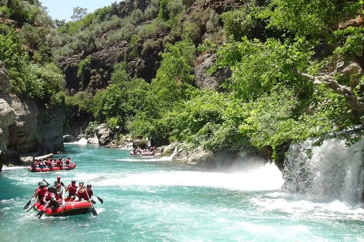 Multiple rafting boats in a canyon river area with waterfall spray and green forest backdrop