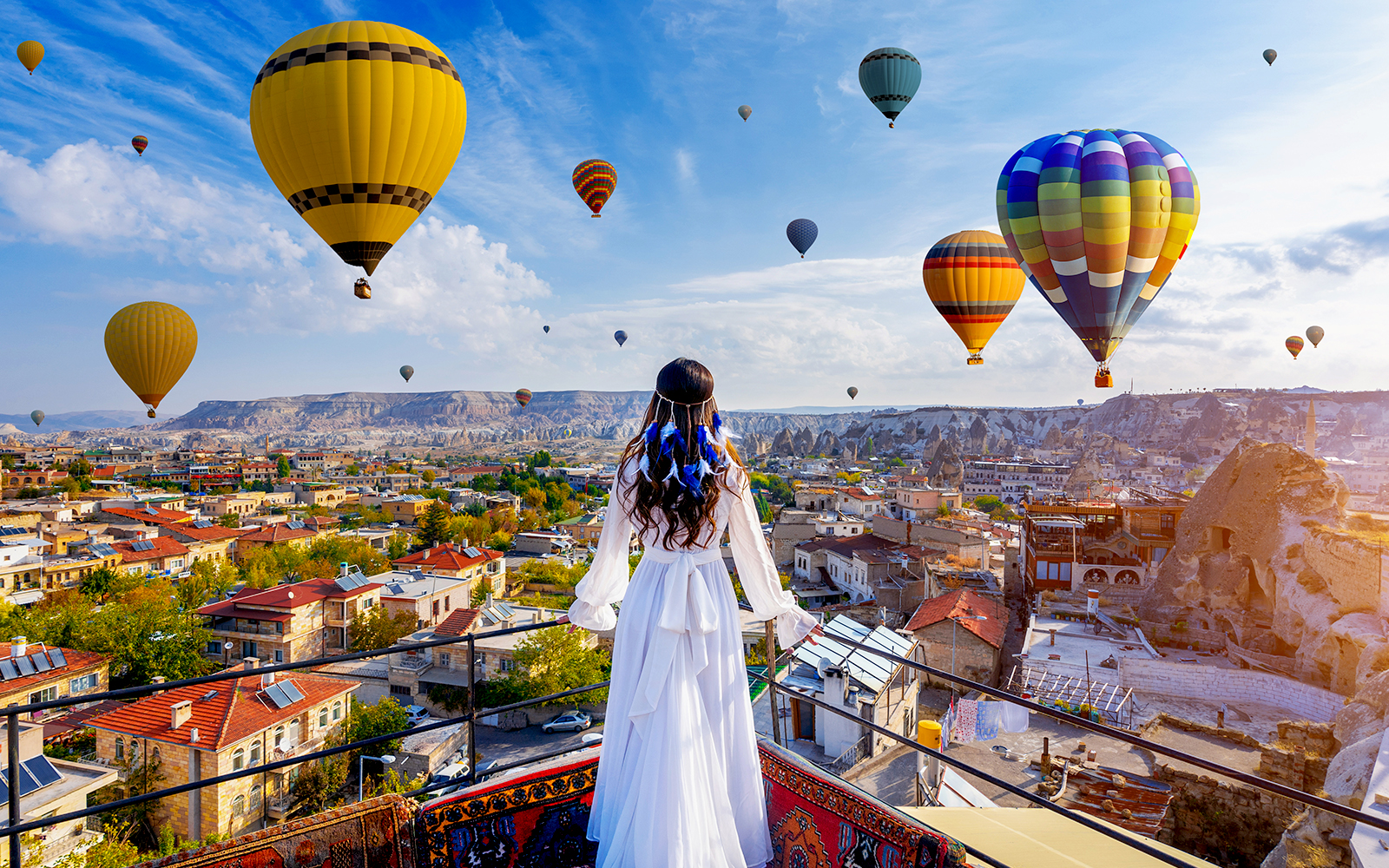 Woman overlooking Cappadocia town and balloons